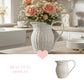 White wicker pitcher with pink flowers on a kitchen counter, with 'Beauty in Display' text and heart icon.

