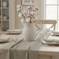 Dining table setting with a woven pitcher containing cotton branches.