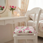 Floral cushion on a chair in a softly lit room with a vanity table and mirror.
