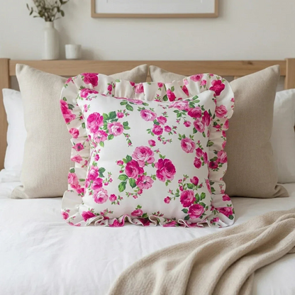 Antique white floral pillow on a bed with neutral bedding and decor.