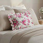Antique white rectangular floral pillow on a bed with a neutral background