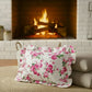Antique white rectangular floral pillow on a couch with a fireplace in the background