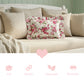 Antique white rectangular floral pillow on a beige sofa with decorative elements and text icons.