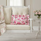 Antique white rectangular floral pillow on a white swing with a vase of flowers in the background