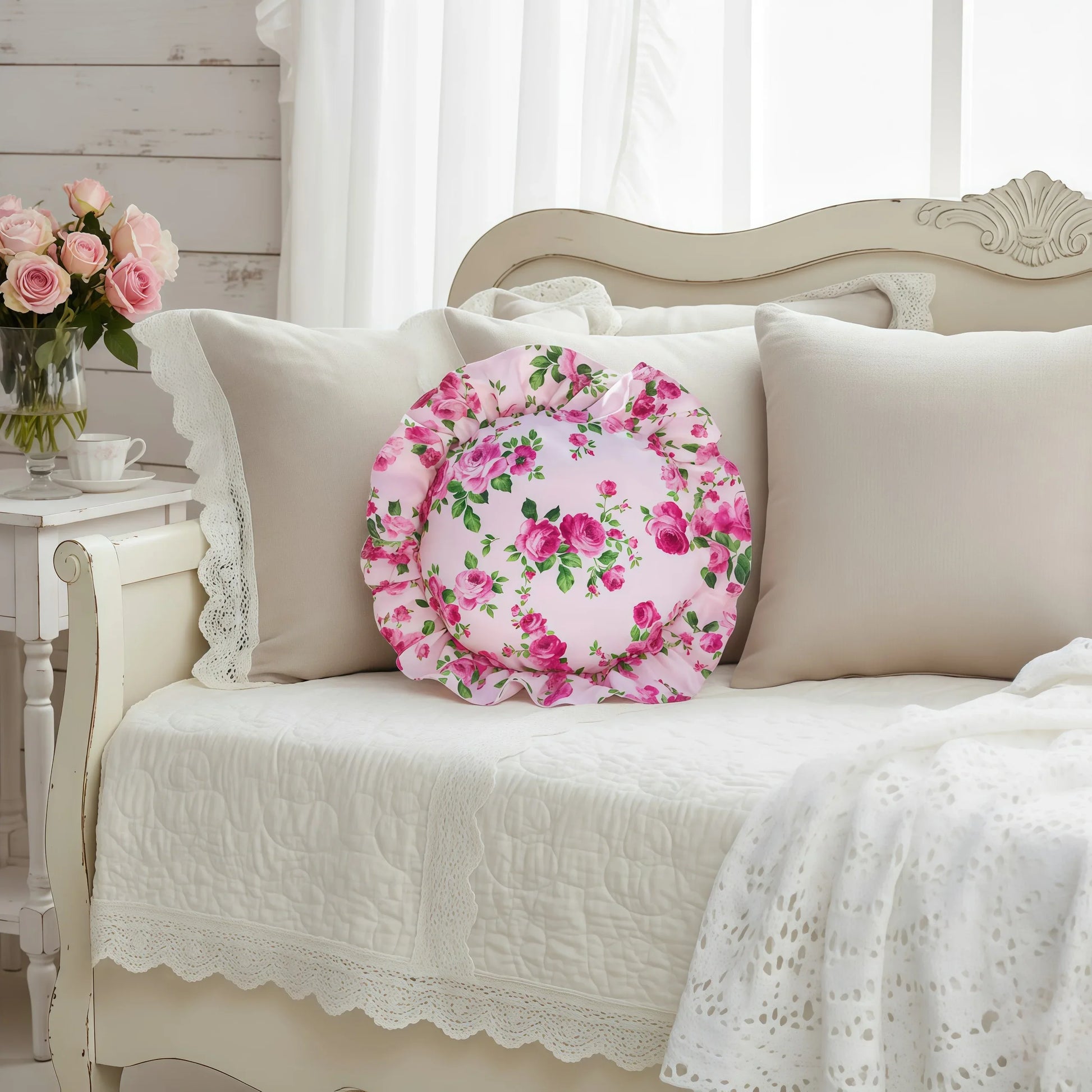 Pale pink circular floral pillow on a beige sofa with a vase of flowers in the background