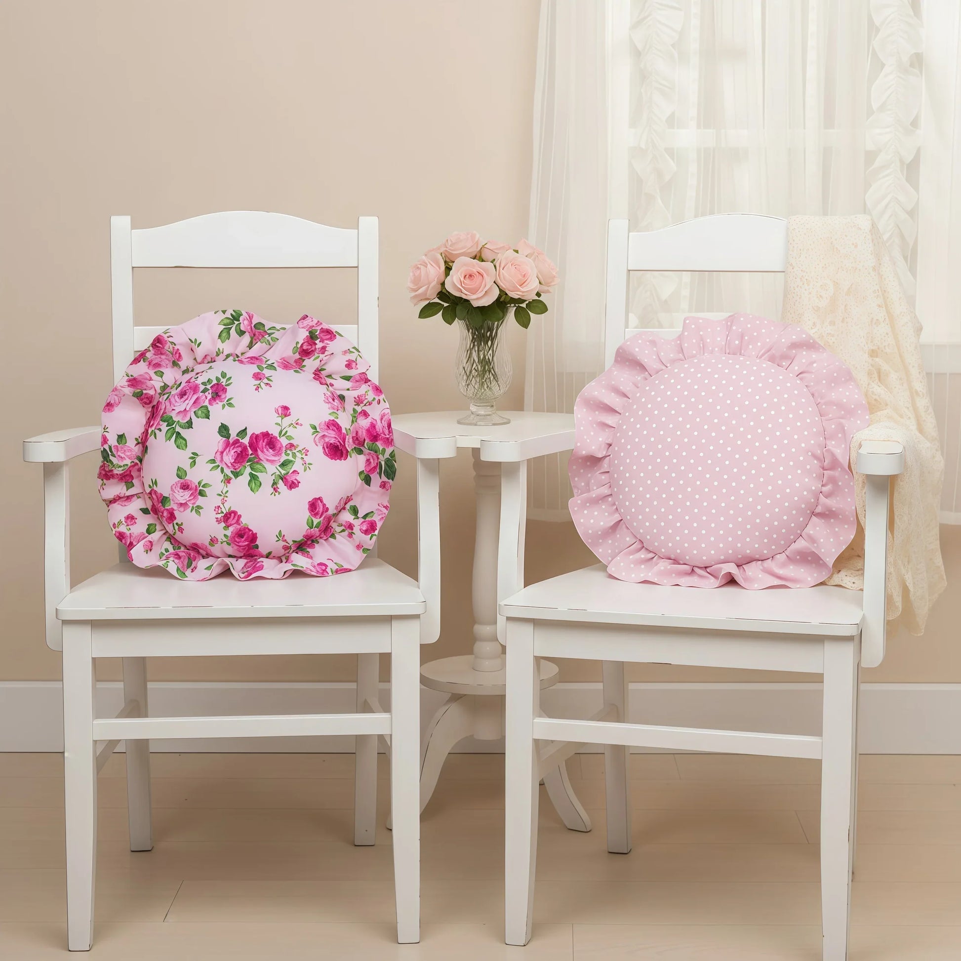 Two white chairs with pale pink floral and polka dot cushions, accompanied by a small table with flowers, on a beige background.