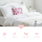 Pale pink floral pillow on a bed with softness, durability, lightness, and breathability icons below.
