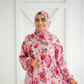 Woman wearing an Isdal prayer dress in the Fleur design, featuring a pink floral rose pattern with a matching integrated hijab.