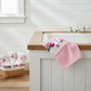 Pink floral towel on a kitchen counter with a basket of towels below.