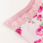 A pink face towel with a floral fleur print and lace detailing, displayed on a white surface.