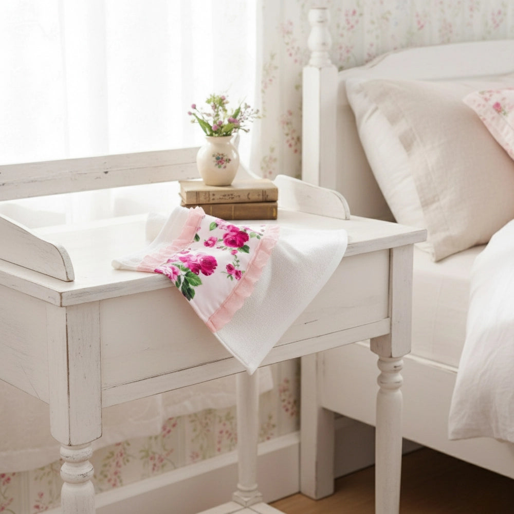 Fleur Face Towel on white wooden bench with floral pattern beside vase in bedroom setting