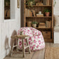 Floral bean bag chair in a cozy room with wooden shelves and books.


