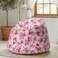 Floral bean bag chair in a room with a plant and window.

