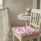 Floral cushion on a chair in a cozy room with a table and flowers.