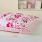 Floral-patterned cushion with pink roses on wooden floor. 