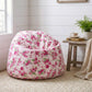 Floral-patterned bean bag chair in a room with a small table and plant.

