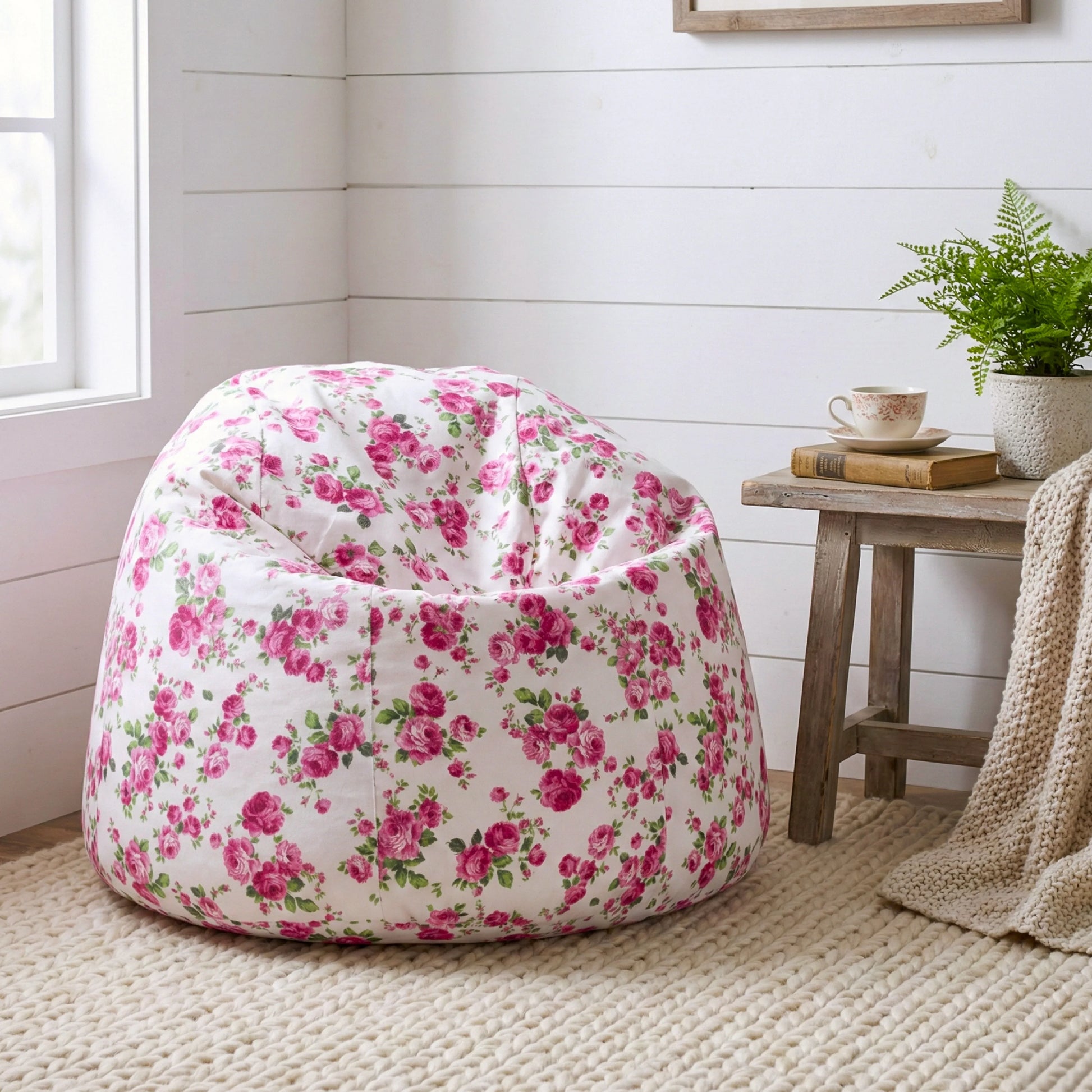 Floral-patterned bean bag chair in a room with a small table and plant.

