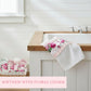 Floral towel on a sink with a basket of more towels in a bathroom setting.