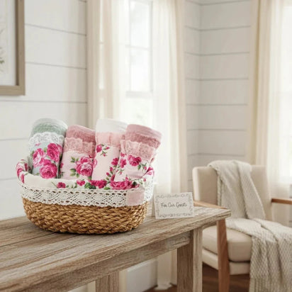 Fleur halfa oval basket of floral towels on a wooden table with a chair and blanket in the background