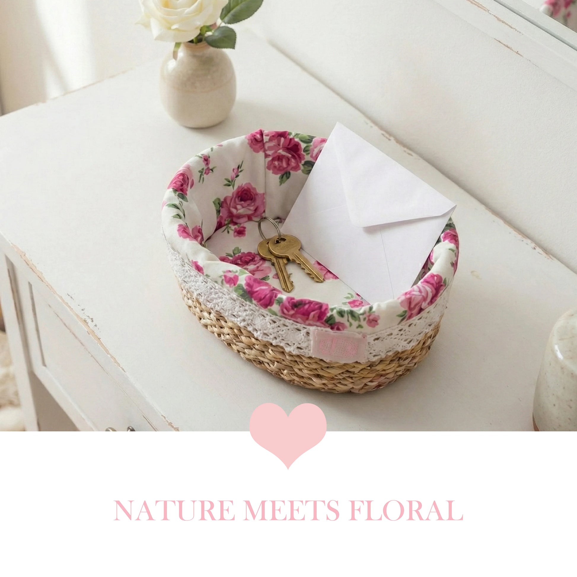 A fleur oval halfa woven basket with a pink rose fabric liner and lace edge, used as an entryway catchall for keys and mail on a white wooden console table.