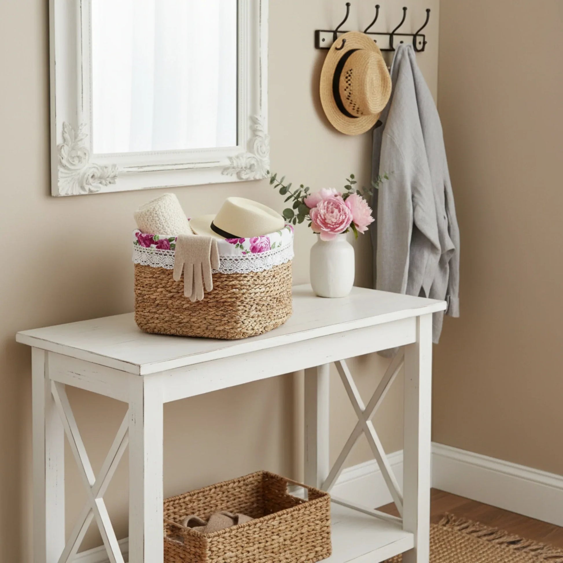 Fleur Halfa Square Basket with pink roses on white wooden table with vase,  large mirror, hat, and coat in the background