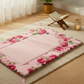 Floral-patterned pink cushion on a tatami mat with a wooden stand and candle in the background.