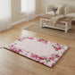 Floral-patterned prayer mat on a wooden floor with a living room in the background
