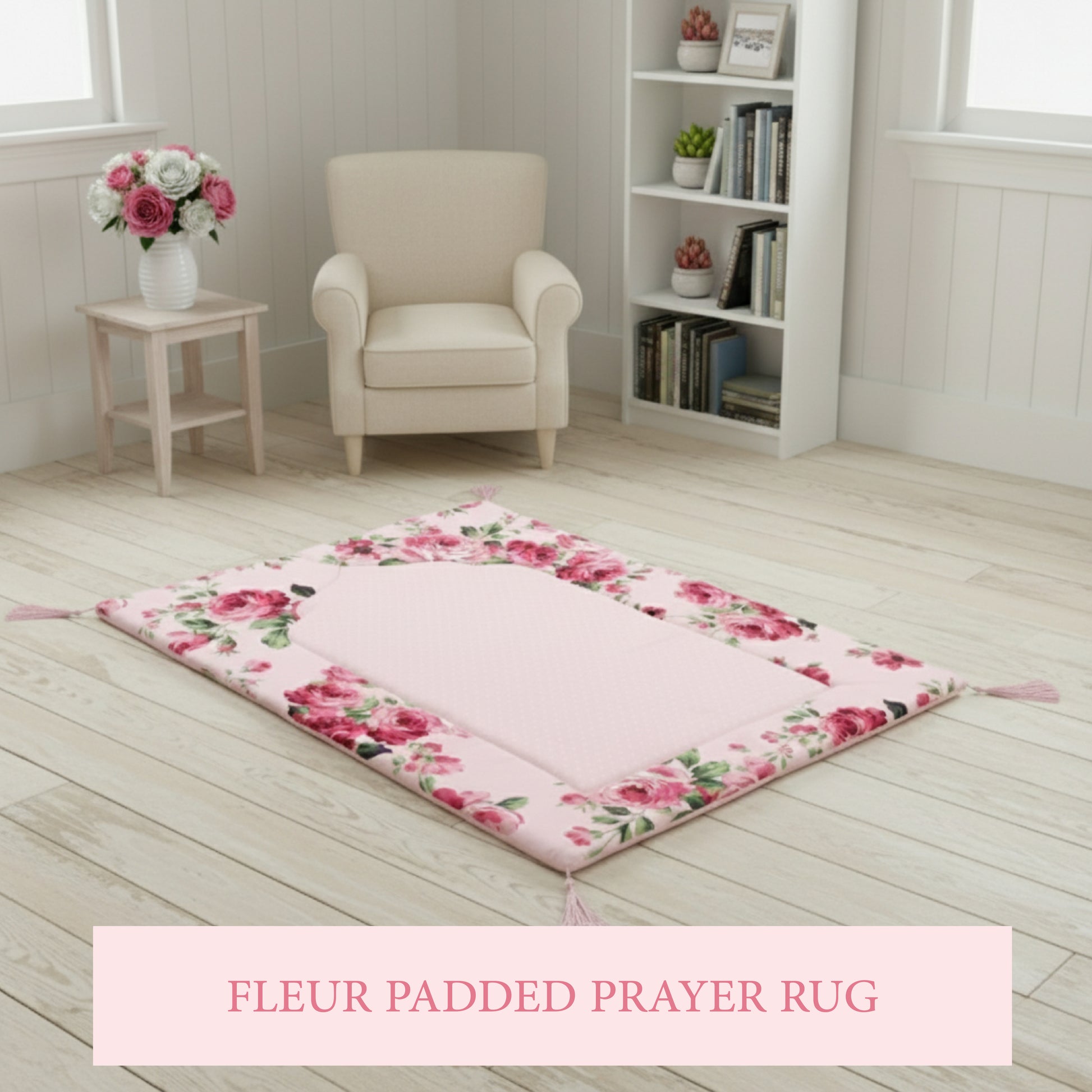 Floral-patterned pink prayer mat on wooden floor with sofa, wooden table on side and vase with flower in it.