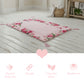 Floral-patterned pink prayer mat on wooden floor with wicker basket on background