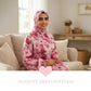 Woman wearing a pink floral hijab and Isdal Prayer dress sitting on a couch with 'Modesty Meets Softness' text.