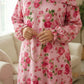 Person wearing a pink floral Isdal Prayer dress holding a necklace indoors.