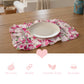 White plate on a pink floral ruffled placemat above icons for fleur print, durable, gabardine fabric, and breathable.