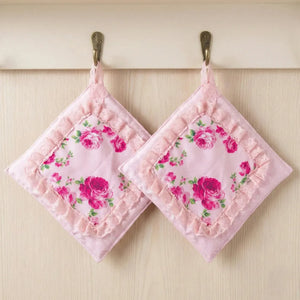 Two pink floral pot holders hanging on a wooden surface.