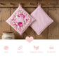 Two pink pot holders with floral design hanging on a wooden wall, with a jar and decorative elements below.