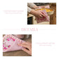 Person holding a pink dish towel with floral design pot holder over a baked dish in a kitchen.
