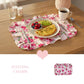 Fleur Placemat floral design with plated food on wooden table featuring Inviting Charm text and heart icon
