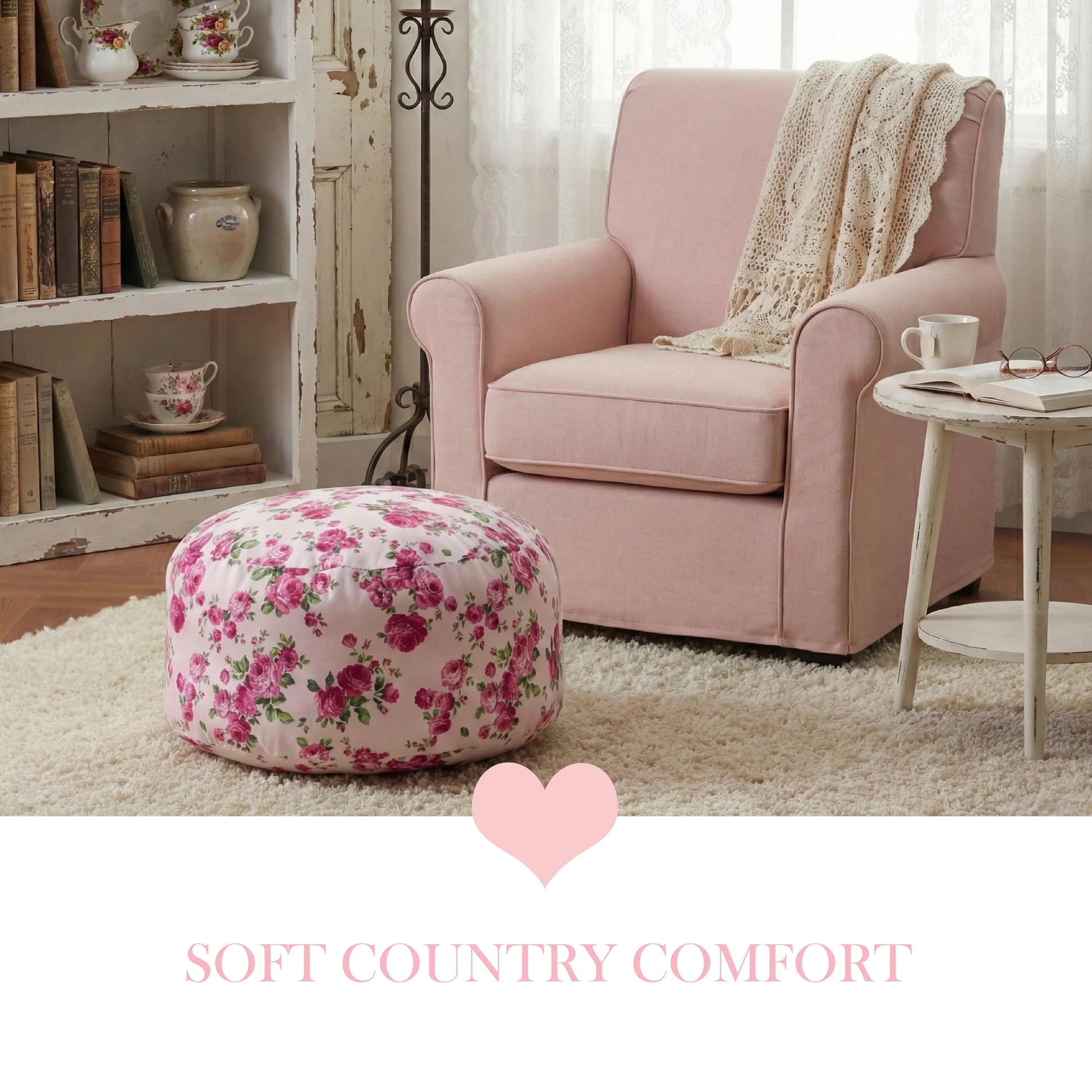 A pink rose fleur pouf on a cream shag rug beside a dusty pink armchair and a white distressed bookshelf in a cozy cottage nook.