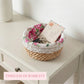 Round fleur basket with rose liner on a white console table, holding keys and a vintage postcard