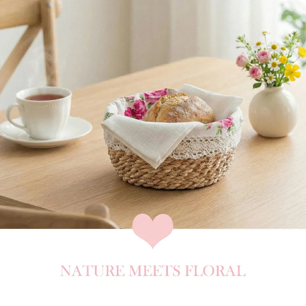 Woven bread basket with bread and flowers on a wooden table, accompanied by a cup of tea.