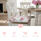 Floral cushion on a chair with a dining table and flowers in the background