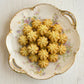 Decorative plate with floral patterns holding petit four cookies on a light wooden surface.
