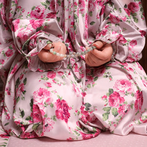 Person wearing a floral dress holding prayer beads.