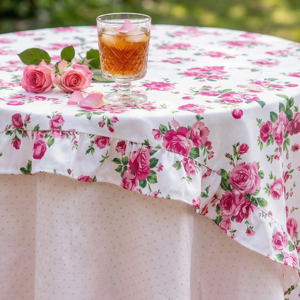 Floral tablecloth with a glass of iced tea and pink roses on a blurred outdoor background