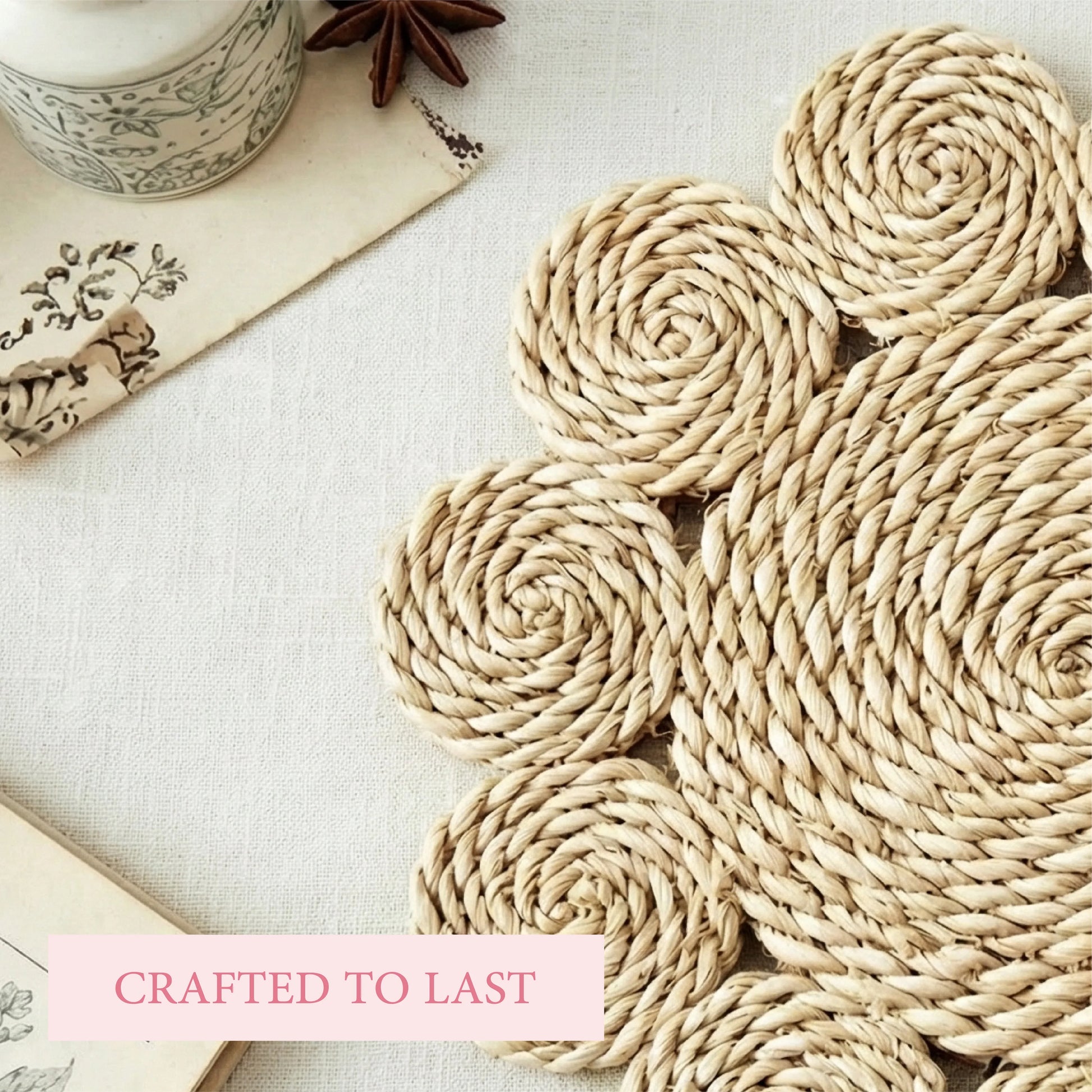 Close-up of a hand-woven flower-shaped placemat on a linen surface with a vintage jar and botanical cards.