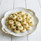 Decorative plate of ghorayeba cookies with pistachios on a white wooden surface