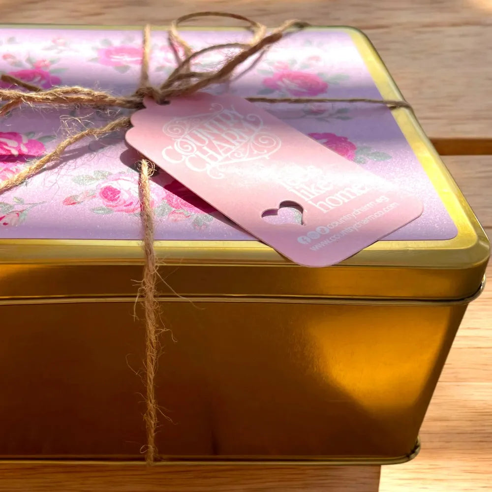 Gold gift box with floral wrapping paper and a pink tag on a wooden surface