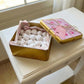 Gold tin filled with powdered sugar cookies on a white surface
