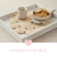 Halfa Flower-Shaped Placemat with tray, mug, cookies, and woven coasters on wooden surface featuring Charm in Every Meal text