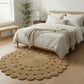 Round woven rug in front of a bed in a bedroom setting
