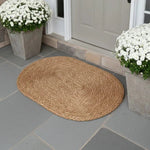 Halfa oval welcome mat placed on stone patio near door with potted plants in outdoor entrance setting